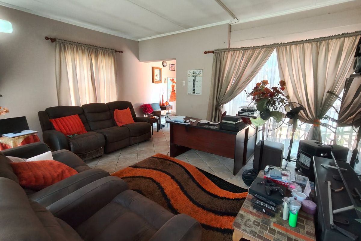 Spacious living area featuring tiled flooring and large windows with curtain rods, offering a versatile layout for relaxation or home office use.