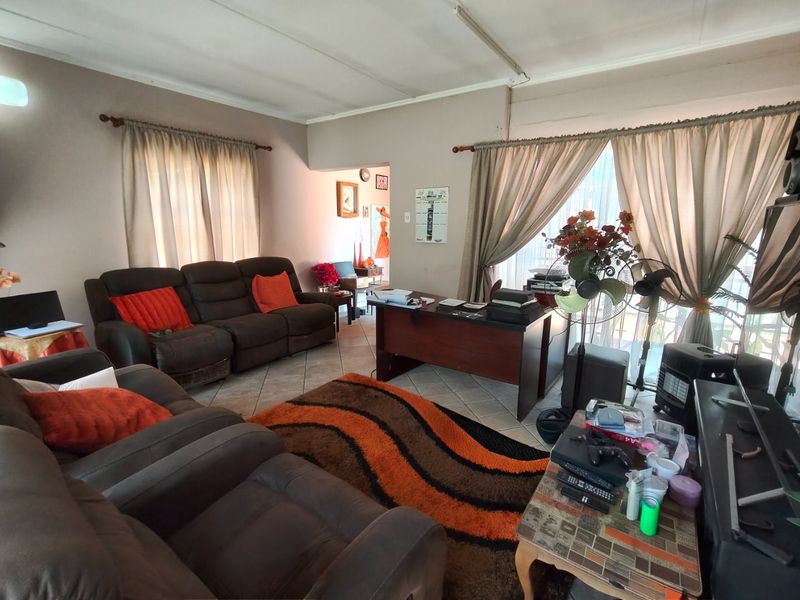 Spacious living area featuring tiled flooring and large windows with curtain rods, offering a versatile layout for relaxation or home office use.