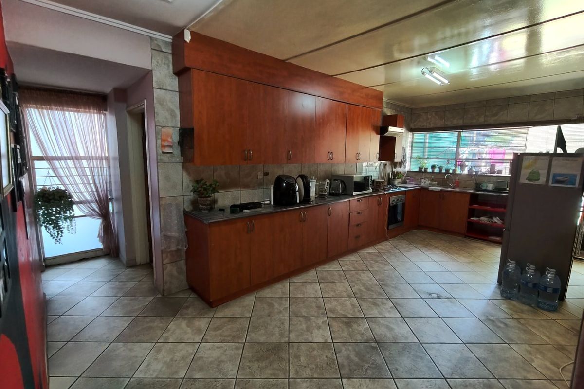 A functional kitchen featuring extensive wooden cabinetry, tiled flooring, and a built-in oven, offering a practical layout with ample storage space.