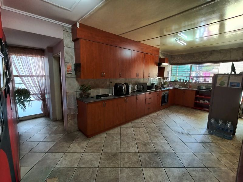 A functional kitchen featuring extensive wooden cabinetry, tiled flooring, and a built-in oven, offering a practical layout with ample storage space.