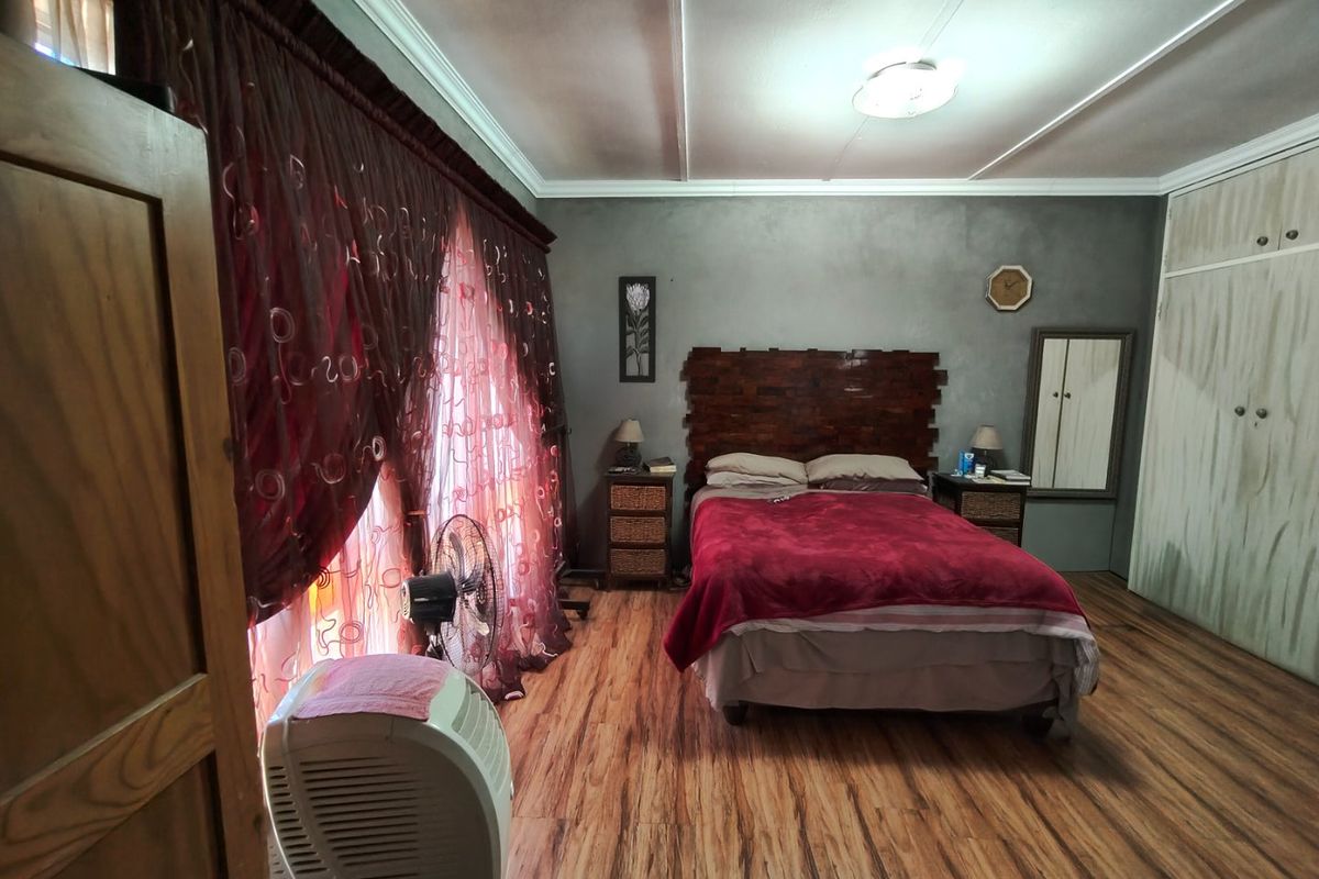 A spacious bedroom featuring laminate flooring, built-in cupboards, and a neutral wall finish, offering a functional layout ready for modern updates.