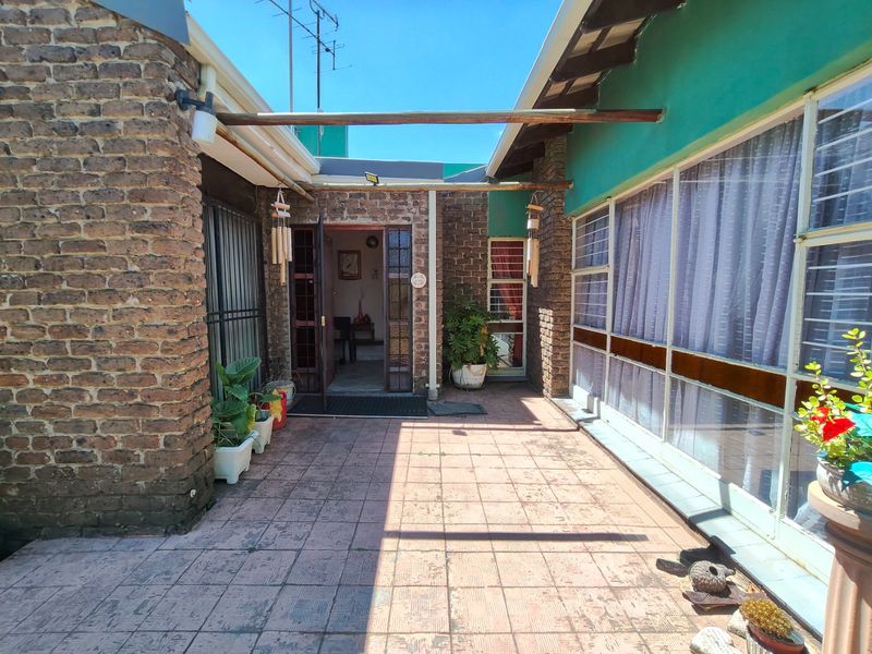 A covered outdoor patio area featuring exposed brickwork, tiled flooring, and direct access to the interior living space.