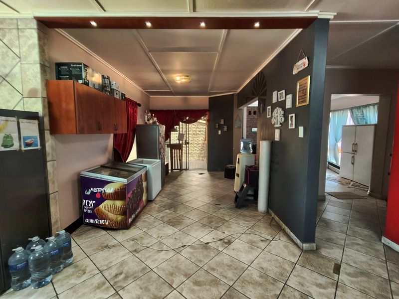 Open plan living area featuring tiled flooring and recessed lighting, currently utilized as a commercial or utility space with potential for residential renovation.