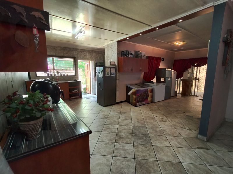 Open plan kitchen and utility area featuring tiled flooring, built-in cabinetry, and direct access to the exterior.