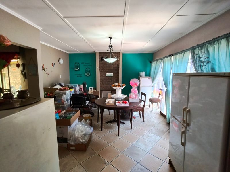 Dining area featuring a brick fireplace, tiled flooring, and ceiling tiles, offering a functional space with potential for cosmetic updates.