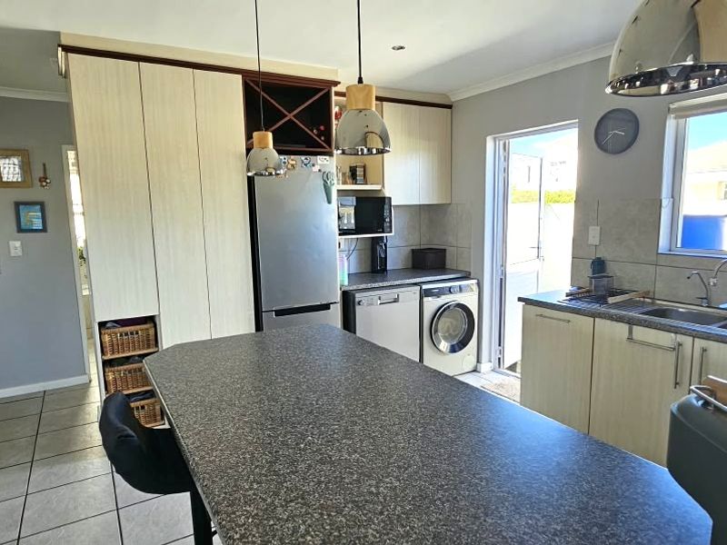 Functional kitchen featuring a central island, ample built-in cabinetry, tiled backsplash, and direct access to the exterior.