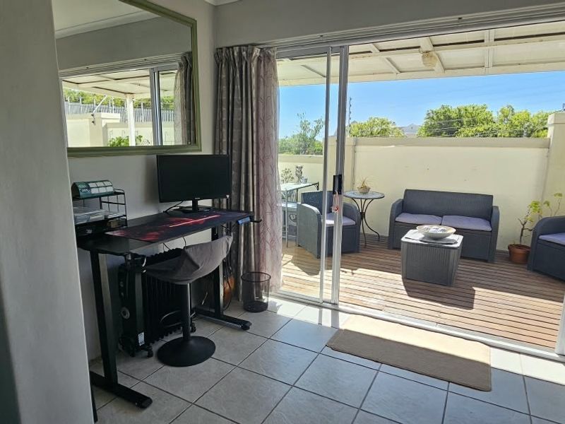 Indoor living area featuring large sliding glass doors that open onto a wooden deck patio, providing a seamless transition to the outdoor space.