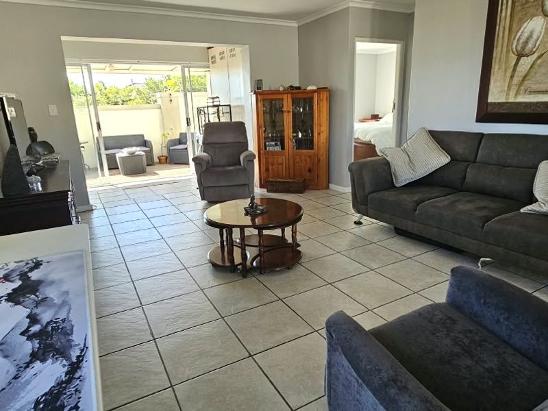 Spacious living room featuring neutral tiled flooring and large sliding glass doors that provide seamless access to an outdoor patio area.