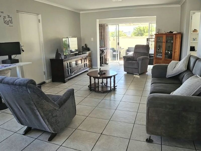 Spacious living room featuring neutral tiled flooring and large sliding glass doors that provide access to the outdoor patio area.