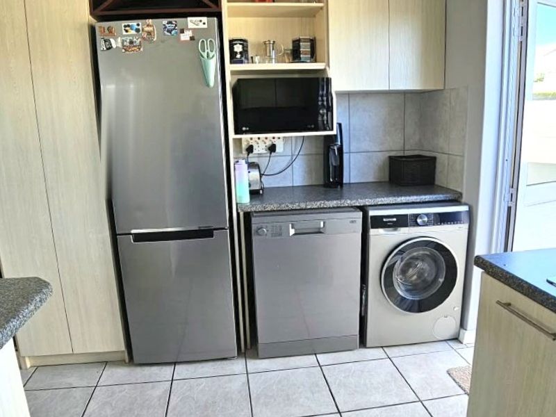 Functional kitchen area featuring laminate cabinetry, granite-look countertops, tiled flooring, and direct access to the exterior through a glass door.