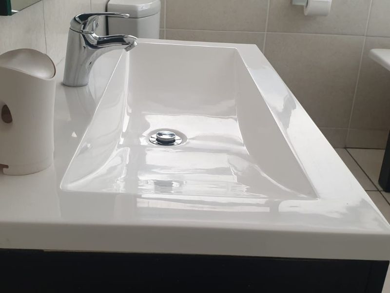 A modern bathroom featuring a sleek rectangular basin with a chrome mixer tap, tiled surfaces, and a freestanding bathtub.