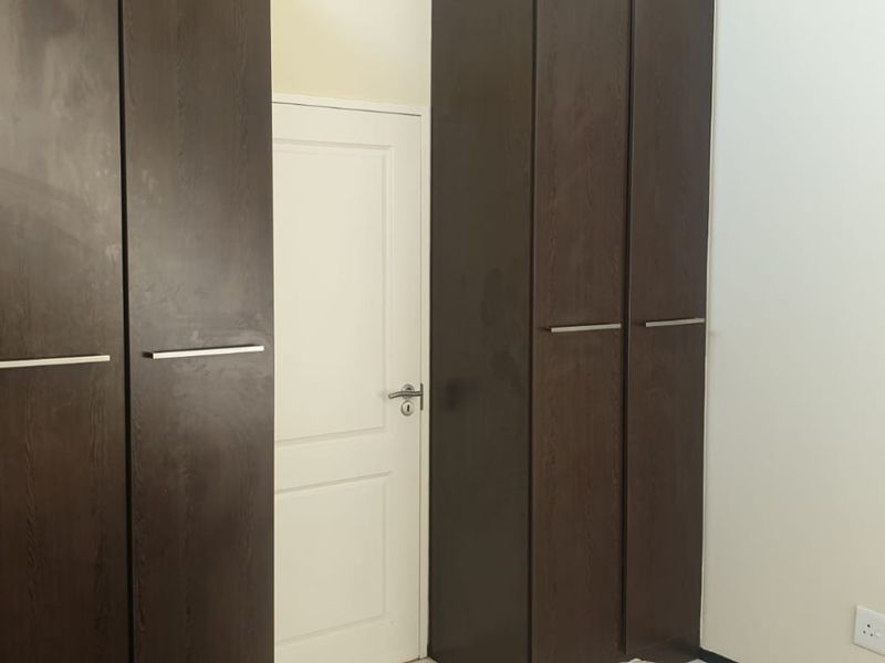A bedroom interior featuring dark wood built-in cupboards and a white internal door.