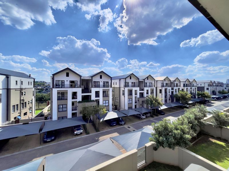 Elevated view of a modern apartment complex featuring multiple residential blocks, covered parking bays, and well-maintained paved driveways.