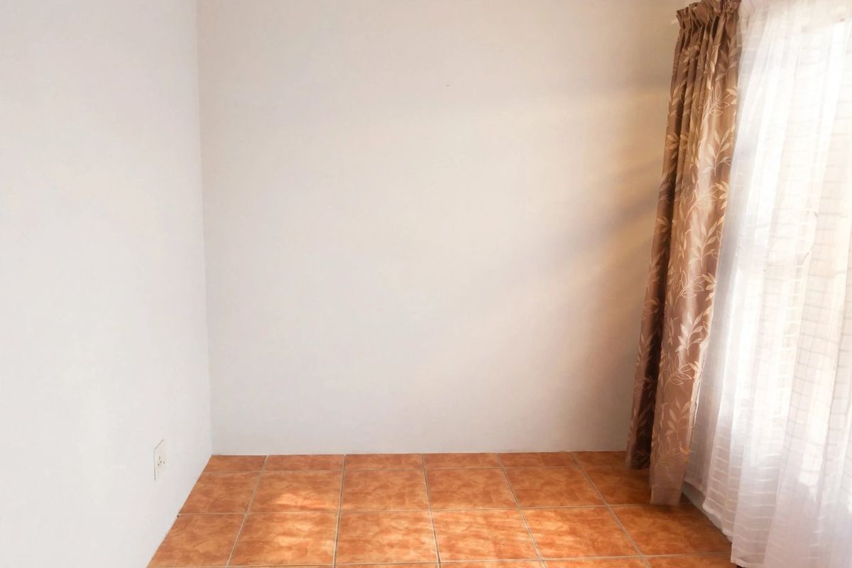 A clean, empty bedroom featuring neutral walls and durable ceramic floor tiles, offering a blank canvas for personalization.