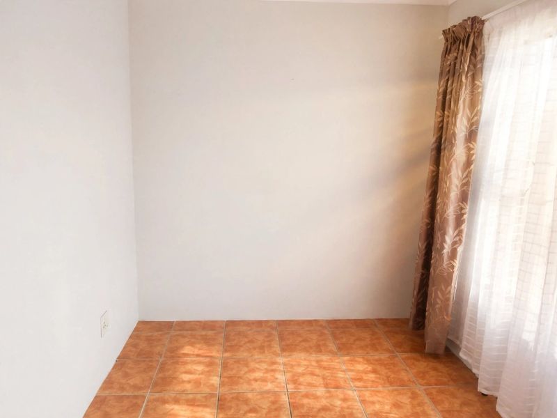 A clean, empty bedroom featuring neutral walls and durable ceramic floor tiles, offering a blank canvas for personalization.