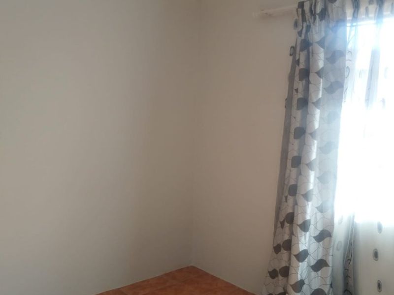 A bright, empty bedroom featuring neutral wall paint, tiled flooring, and decorative cove cornicing, offering a clean canvas for personalization.