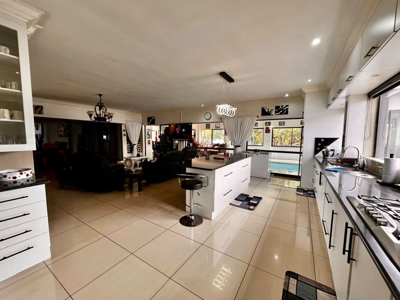 Spacious open-plan living area featuring a modern kitchen with a central island, sleek cabinetry, and tiled flooring, seamlessly flowing into the lounge space.