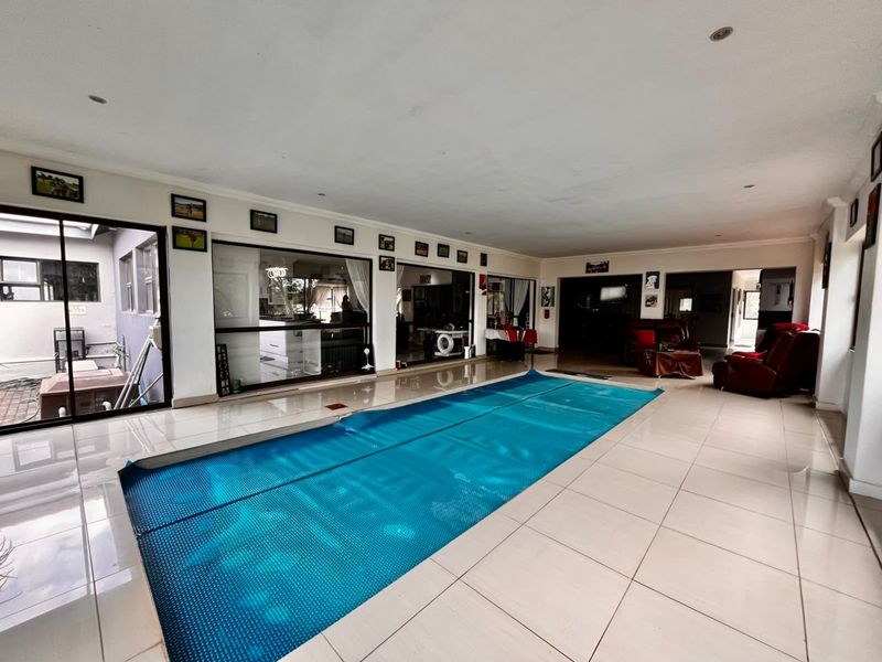 Spacious indoor pool area featuring large format floor tiles, recessed lighting, and expansive sliding glass doors providing seamless access to the surrounding living spaces.