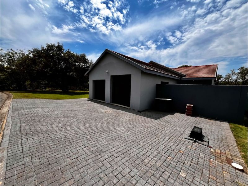 A well-maintained double garage featuring a paved driveway and a modern tiled roof, set within a clean exterior environment.