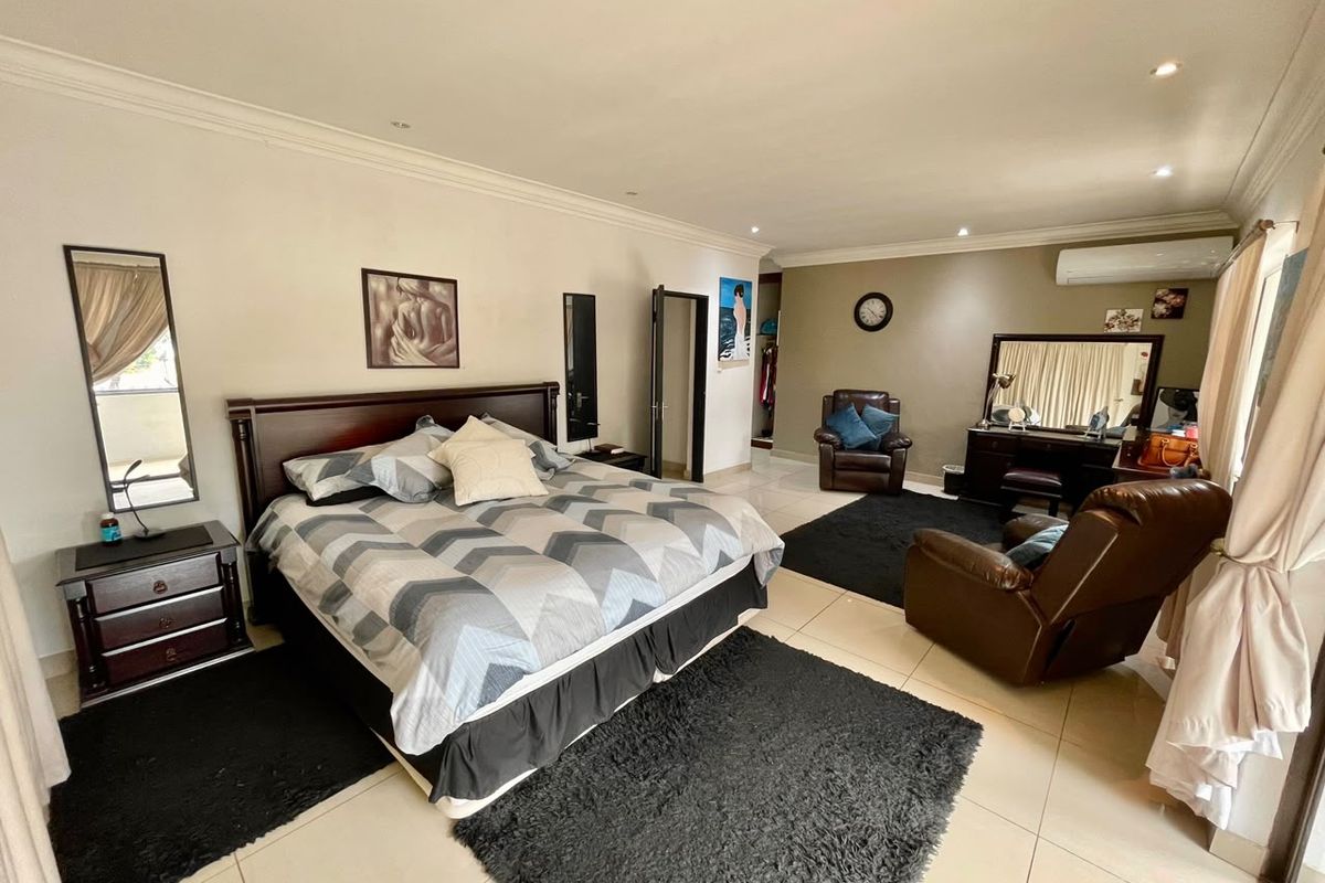 Spacious bedroom featuring tiled flooring, recessed downlighting, and a wall-mounted air conditioning unit.
