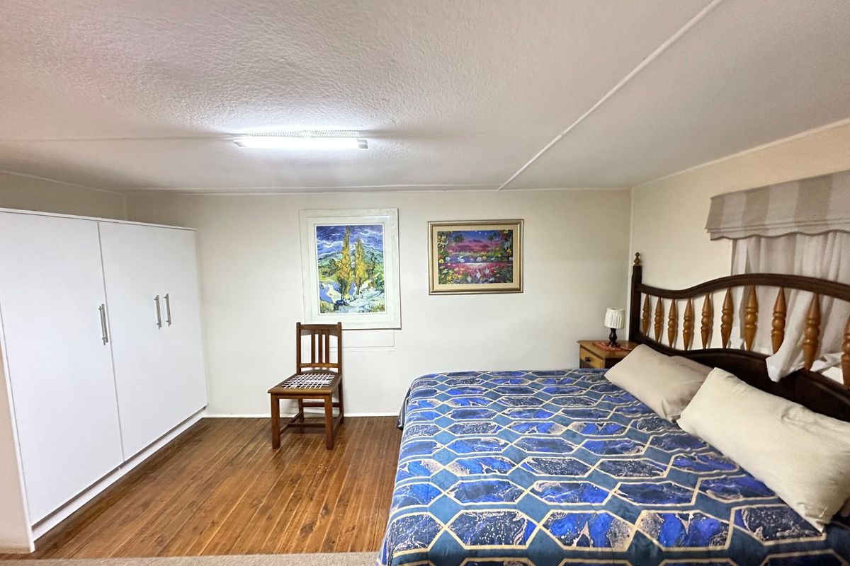 A bedroom featuring timber flooring, a built-in wardrobe, and a functional layout with neutral wall finishes.
