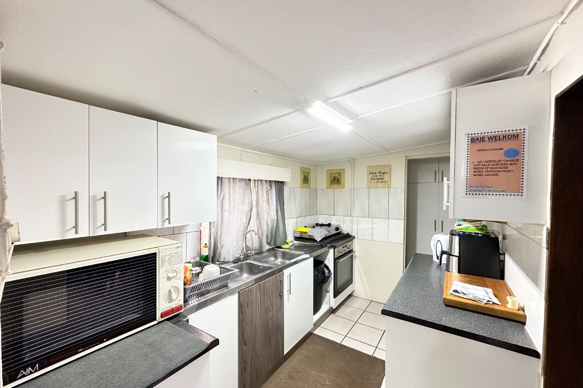 Functional kitchen featuring white cabinetry, double basin sink, tiled splashbacks, and a freestanding stove with ample counter space.