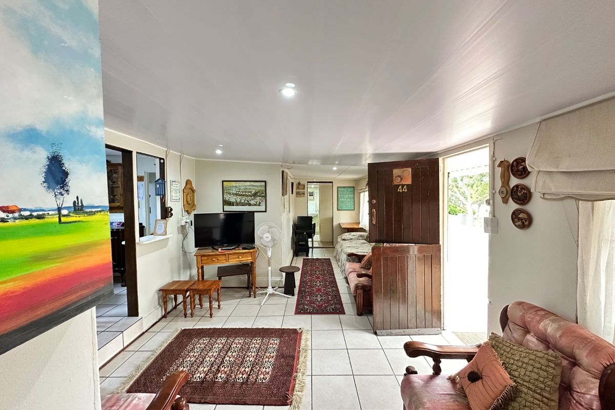 A living room area featuring tiled flooring, a classic stable-style entrance door, and a pass-through window connecting to an adjacent space.