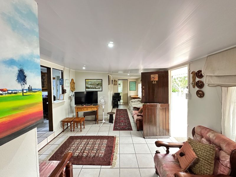 A living room area featuring tiled flooring, a classic stable-style entrance door, and a pass-through window connecting to an adjacent space.