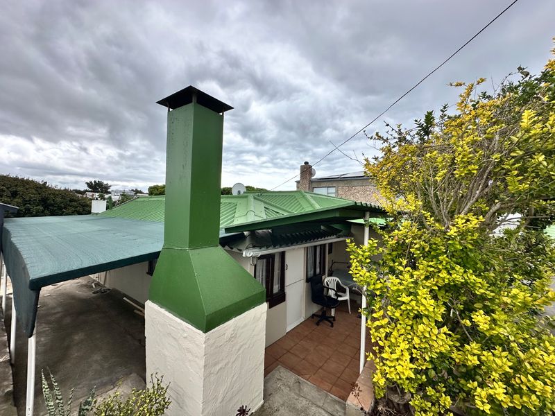 Rear exterior view of the property featuring a tiled patio area, metal roofing, and a prominent chimney stack.