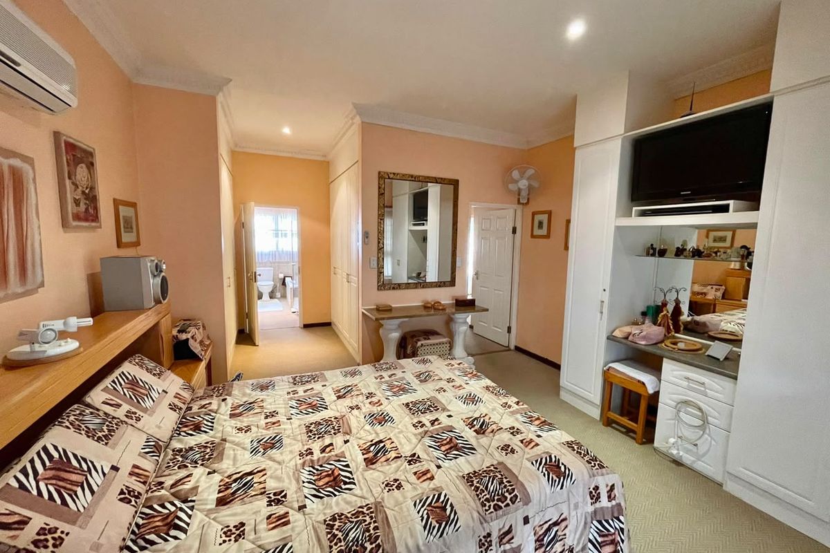 Spacious bedroom featuring built-in cabinetry, air conditioning, and direct access to an en-suite bathroom, offering a functional layout with neutral finishes.