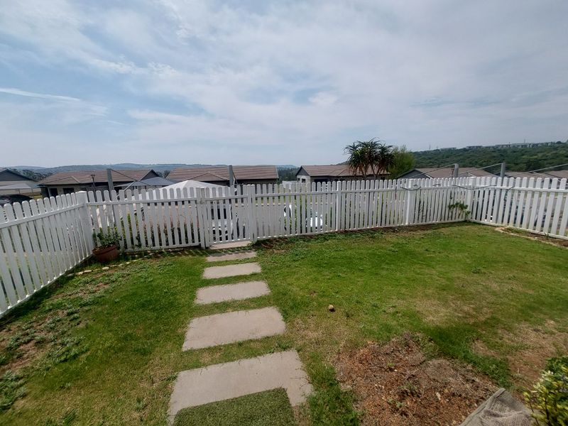 A private garden area featuring a white picket fence, a paved walkway, and a lawn with views of the surrounding estate.