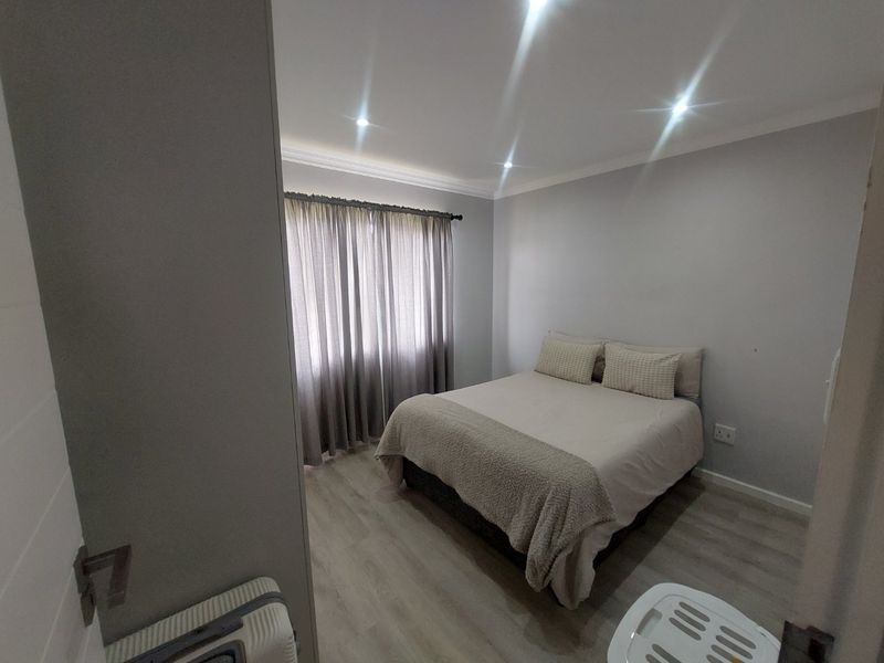 A well-maintained bedroom featuring modern laminate flooring, recessed downlighting, and neutral wall finishes, providing a clean and comfortable living space.