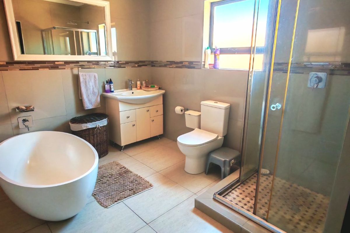 Modern bathroom featuring a freestanding bathtub, glass-enclosed shower, vanity with basin, and neutral wall and floor tiling.