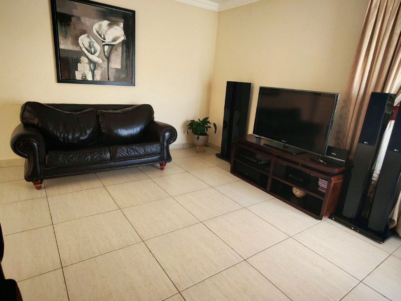 A living room featuring neutral tiled flooring and decorative crown molding.