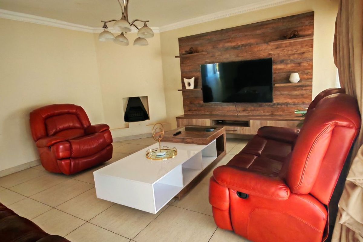 A comfortable living room featuring a built-in fireplace, a modern wood-look media wall unit, tiled flooring, and decorative ceiling molding.