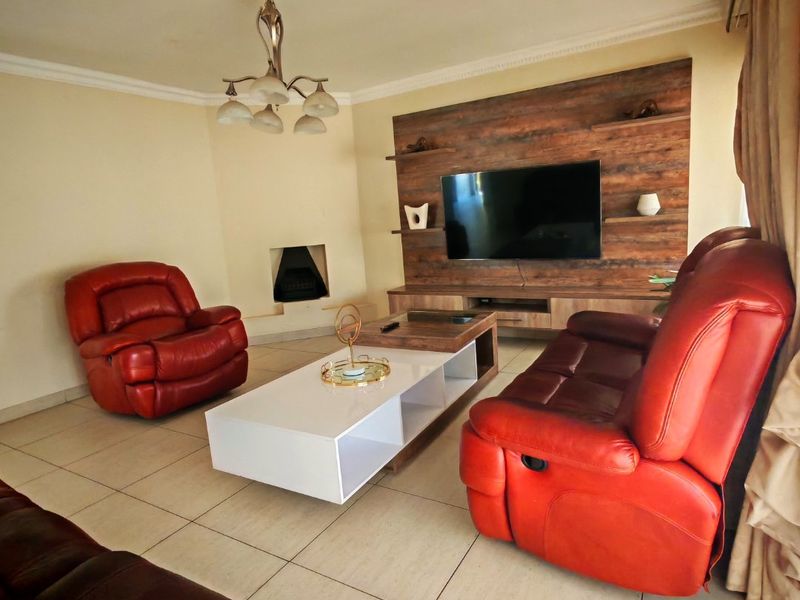 A comfortable living room featuring a built-in fireplace, a modern wood-look media wall unit, tiled flooring, and decorative ceiling molding.