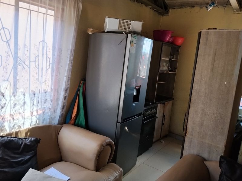 A compact kitchen area featuring tiled floors and built-in cabinetry, currently showing signs of wear and requiring cosmetic updates to the walls and ceiling.