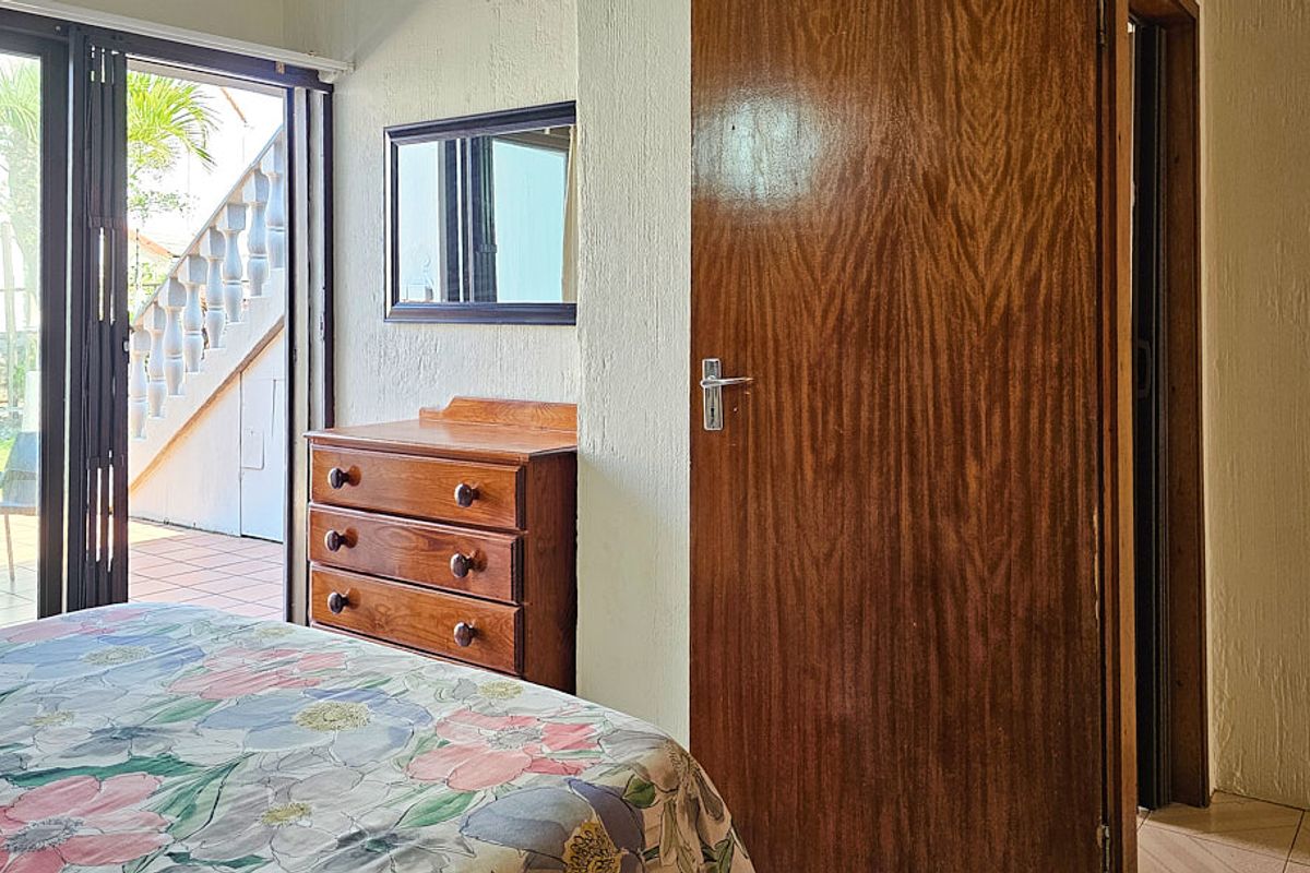 Bedroom featuring textured walls, tiled flooring, and a sliding glass door providing access to an outdoor patio area.