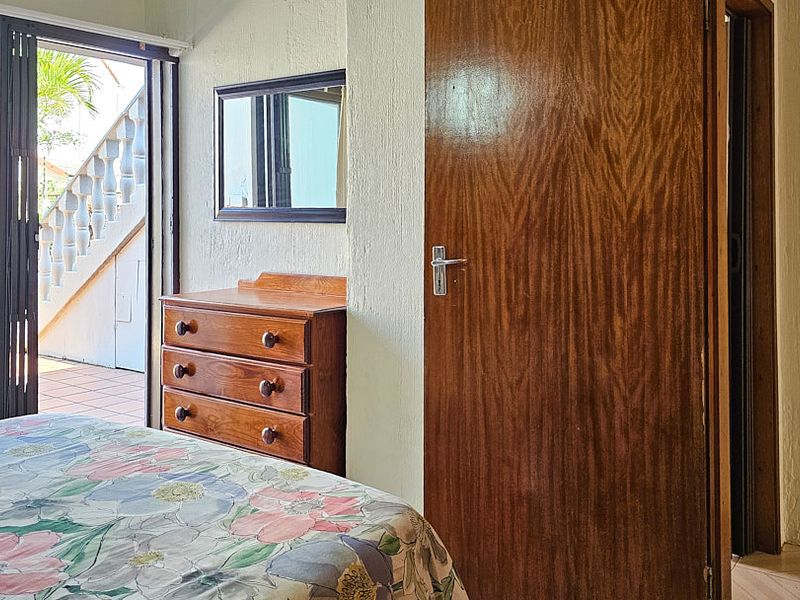 Bedroom featuring textured walls, tiled flooring, and a sliding glass door providing access to an outdoor patio area.