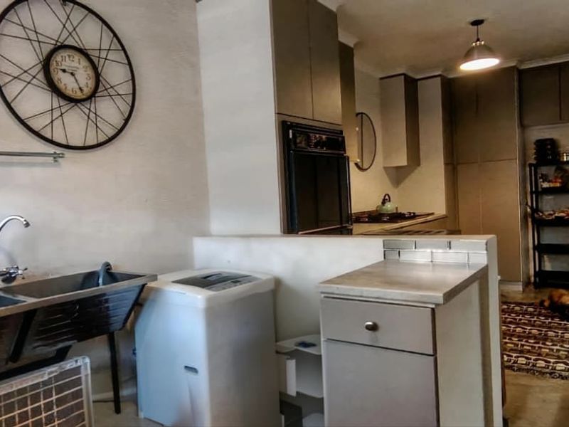 A functional scullery area featuring a double stainless steel sink, built-in cabinetry, and an integrated oven, providing practical workspace adjacent to the main kitchen.