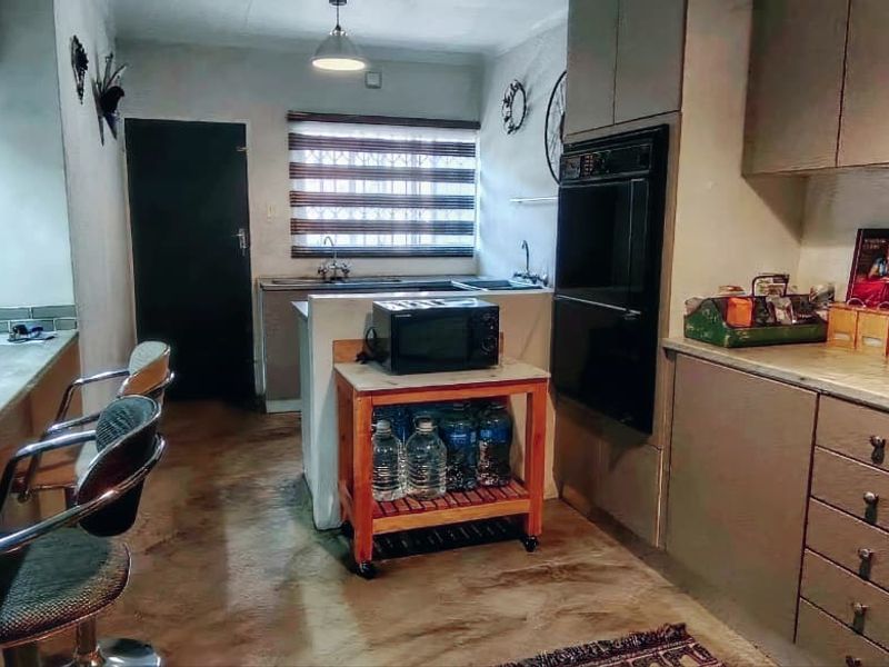 Functional kitchen featuring built-in cabinetry, integrated oven, gas hob, and a breakfast counter, offering a practical layout with potential for modern updates.