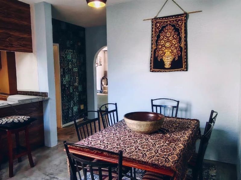 Open plan dining area adjacent to a kitchen with a breakfast bar and arched doorway access.
