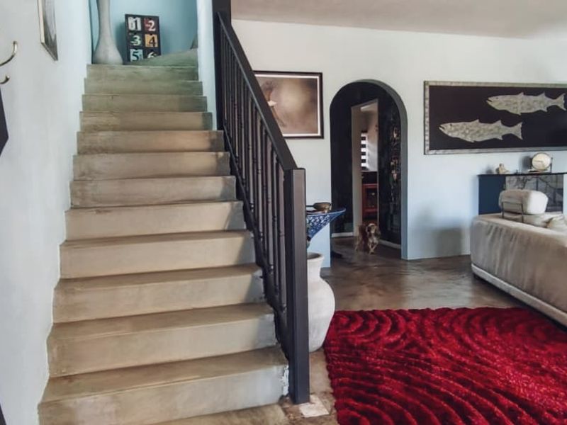 Spacious living area featuring a central staircase with a metal balustrade and an arched doorway leading to adjacent rooms.