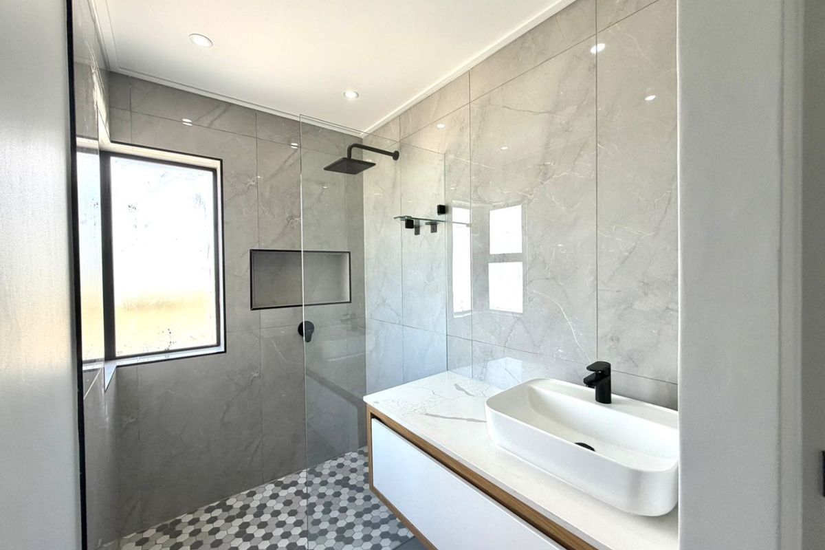Modern bathroom featuring a walk-in shower with a recessed niche, floating vanity with a vessel sink, and contemporary grey marble-look wall tiles.