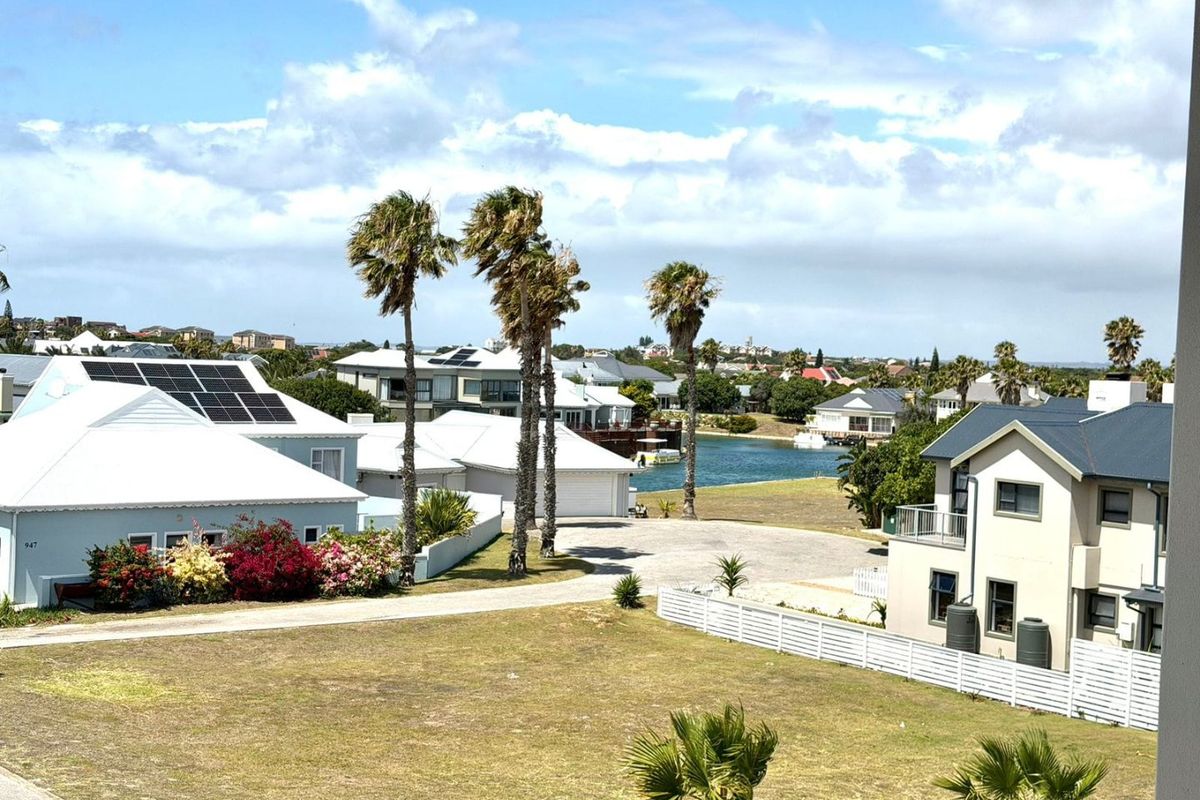 Elevated view overlooking a residential estate with surrounding homes, landscaped gardens, and a nearby water feature.