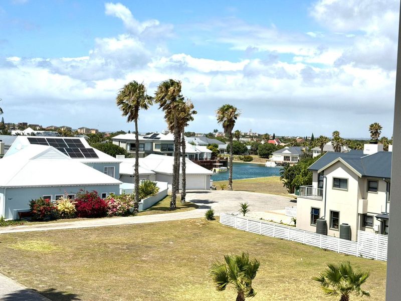 Elevated view overlooking a residential estate with surrounding homes, landscaped gardens, and a nearby water feature.