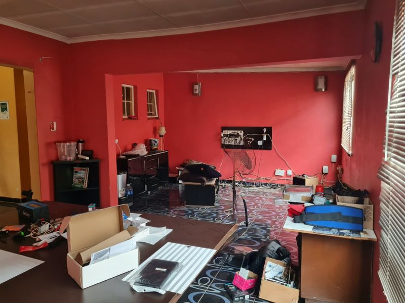 A living room space featuring tiled flooring and venetian blinds, currently requiring cosmetic updates and electrical maintenance to improve the overall finish.