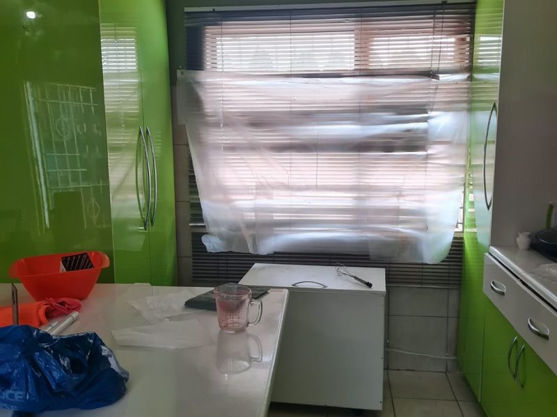 Kitchen area featuring high-gloss green cabinetry and tiled flooring, requiring minor repairs to window treatments.