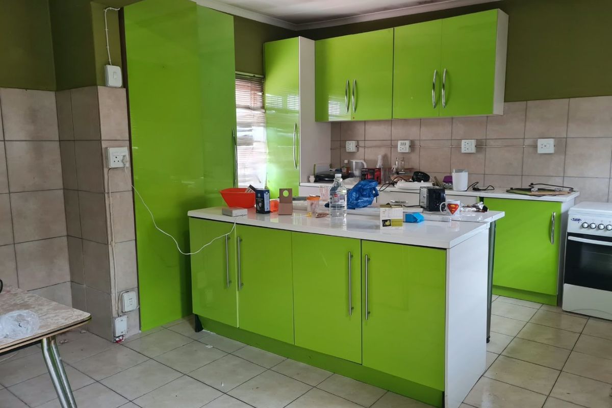 Kitchen featuring bright green cabinetry, a central island, tiled flooring, and a built-in oven, requiring some cosmetic updates and electrical finishing.