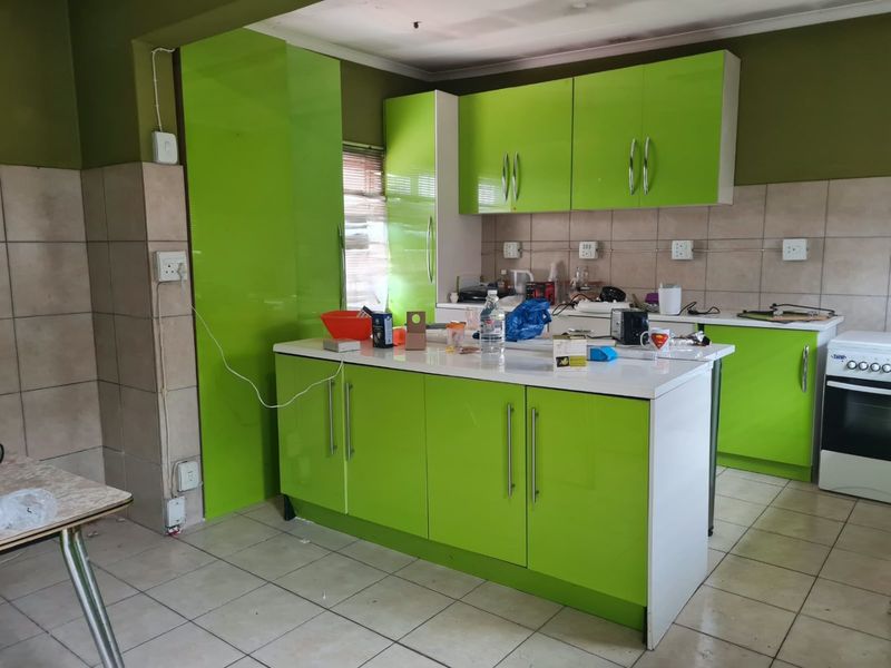 Kitchen featuring bright green cabinetry, a central island, tiled flooring, and a built-in oven, requiring some cosmetic updates and electrical finishing.